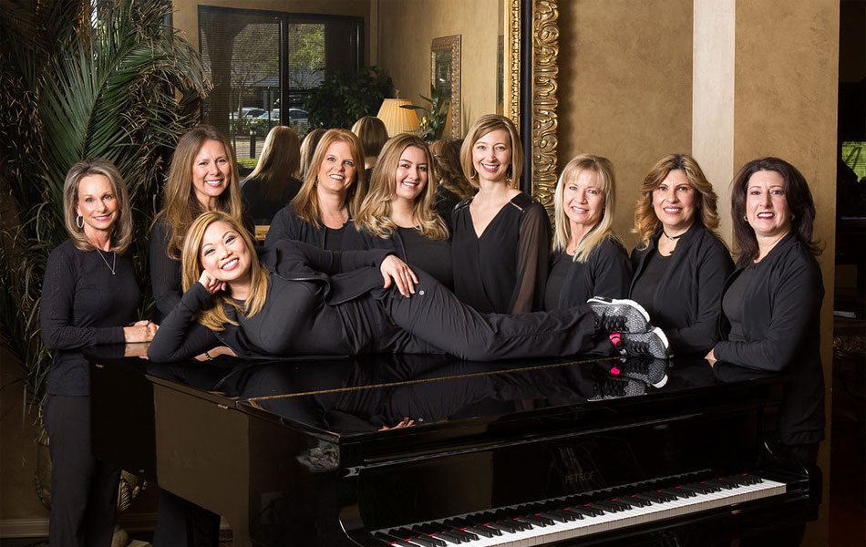 The staff at Smile Texas posing around the piano in the reception area.